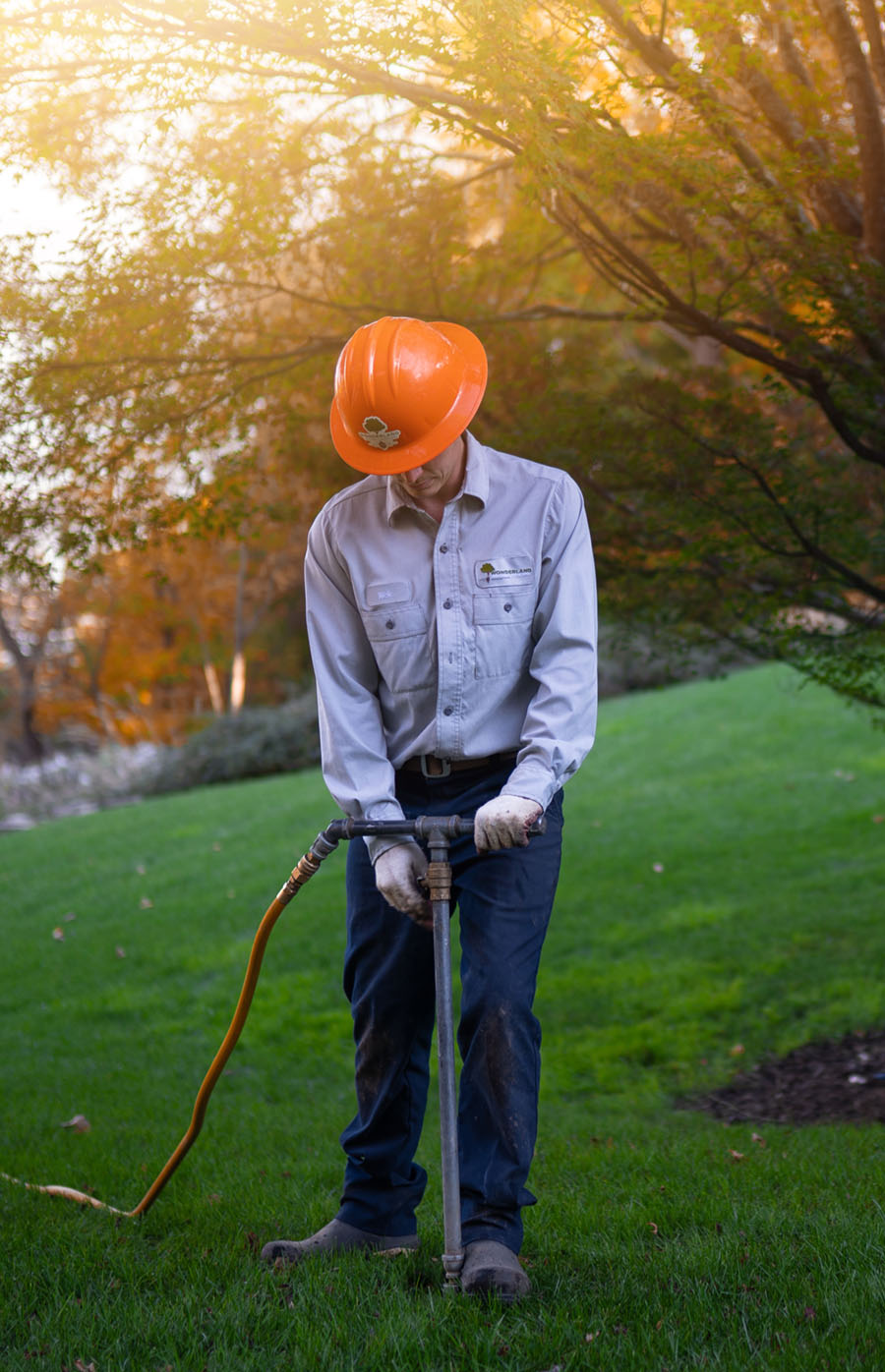 landscape technician adding fertilizer to lawn